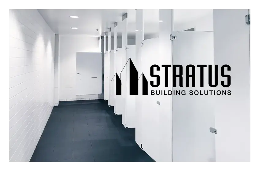 Clean office bathroom with clean white walls and stall doors and the Stratus logo in black